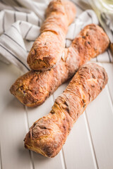 Crusty rustic baguette on white table.