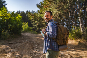 adult male camper with a backpack walking through the forest