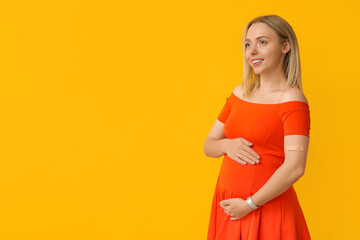 Obraz premium Young pregnant woman after vaccination on yellow background