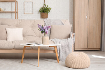 Vase with lilac flowers and magazine on coffee table in living room