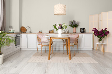 Vases with beautiful lilac flowers in kitchen