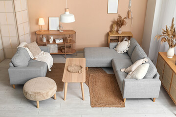 Interior of stylish living room with grey sofas, wooden table and pampas grass