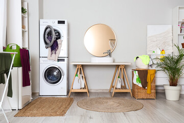 Interior of bathroom with washing machines, dryer and laundry basket