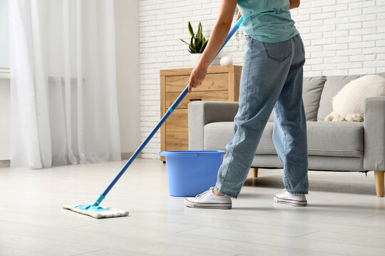 Woman mopping wooden floor in living room