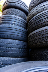 Obraz premium Stack of old, worn and damaged tires lying in a landfill. Decreased road safety and environmental pollution from rubber waste