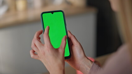 Woman zooming greenscreen smartphone watching social media at kitchen close up.