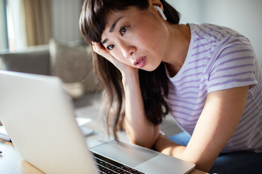 Stressed woman working on laptop at home with hand on face