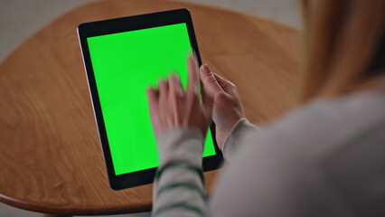 Hands swiping green screen tablet in apartment close up. Woman touching mockup 