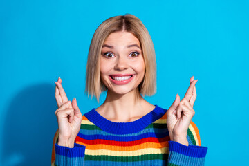 Portrait of pretty young girl crossed fingers wear striped pullover isolated on blue color...