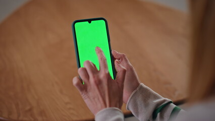 Girl browsing greenscreen cellphone app sitting apartment desk close up. 