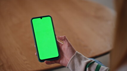 Smartphone user scrolling green screen at home apartment closeup. Woman hands
