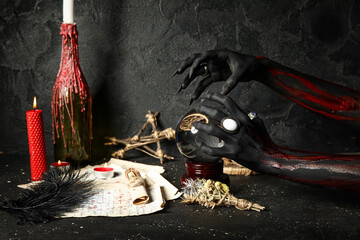 Bloody witch hands with crystal ball and magic attributes on grunge black background. Halloween...