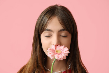 Beautiful young woman with gerbera flower on pink background