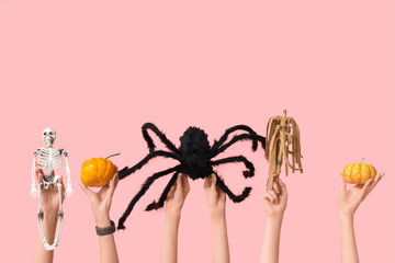 Female hands with skeleton, pumpkins, stick and spider on pink background. Halloween celebration