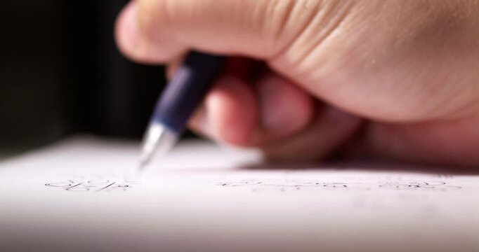 Blurry close-up shot of an individual writing some notes on a piece of paper using a pen.
