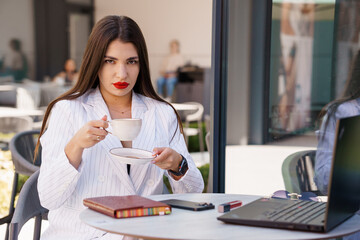 Confident Business Woman Enjoying Coffee While Working Remotely Outdoors in Stylish Attire