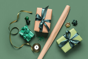 Christmas gift boxes with packing materials and different decorations on green background