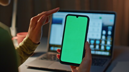 Fingers scrolling chroma key smartphone at evening home close up. Unknown woman