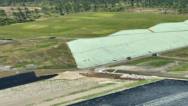 Waste management concept. Large landfill site with bulldozers burying trash under ground. Harmful impact of modern consumerism on environment