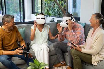 Using VR headsets, senior diverse friends enjoying virtual reality experience together, at home