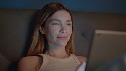 Sleepy girl reading ebook lying dark bedroom close up. Woman looking on tablet