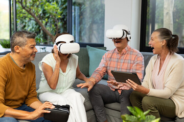 Using VR headsets, senior diverse friends enjoying virtual reality experience together, at home