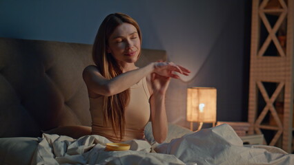 Girl moisturizing arms skin at bedtime home. Happy woman applying cream on hands