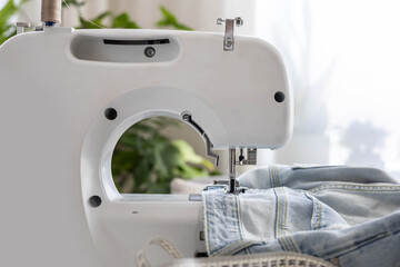 Workplace with a sewing machine. There are old blue jeans on the table.