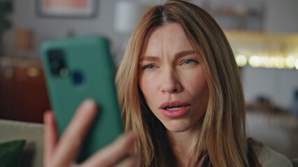 Portrait emotional woman talking at smartphone video call sitting living room.