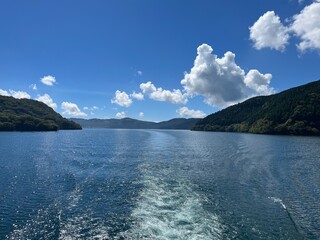 Scenic view of Lake Ashi in Hakone, Japan with clear blue water, lush green mountains, and bright summer sky, capturing the beauty of nature and peaceful lakeside landscape