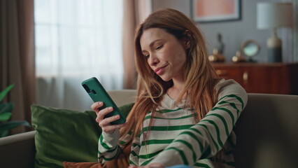 Disappointed woman reading cellphone message in apartment living room close up.