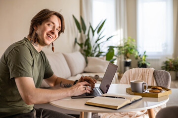 Young stylish man working on a laptop at home. Freelance concept, remote work.