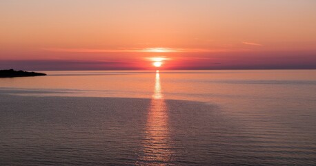 Fototapeta premium Serene sunset over calm ocean waters with a glowing horizon.