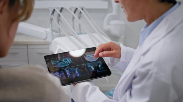 Dentist showing dental x-rays on tablet at stomatology consultation closeup. 