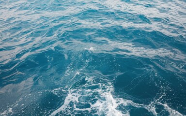 Vast blue ocean waves with white foam forming under the sunlight.