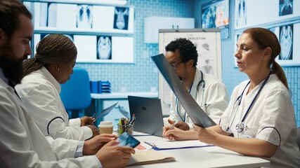 Fototapeta premium Medical expert reviews x ray results and discusses disease prevention during a meeting with healthcare staff, treatment options. Radiology doctors analyzing scans for diagnostic. Camera B.