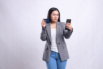 Naklejka premium beautiful young office lady asia disgusted to smartphone hold cellphone smartphone and hold credit debit member card wearing gray suit isolated on white background. for communication, finance