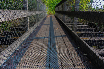 A low angle image of a very old wooden foot bridge with protective metal grating. 