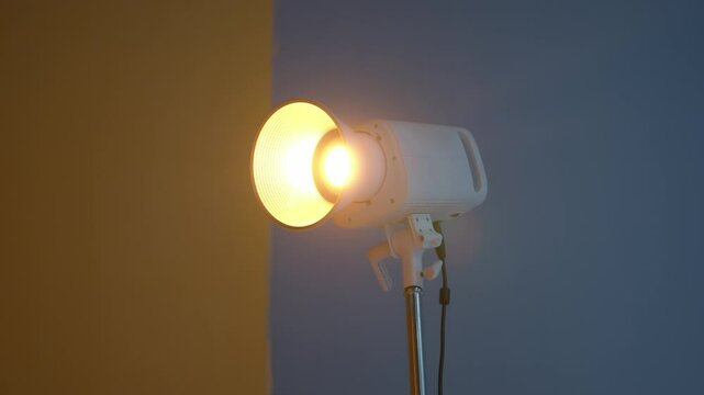 Warm light studio lamp with an extender and a bright light. Professional video lighting, production of an advertising campaign, movies, videos, or short films, warm LED cinema light, Fresnel light