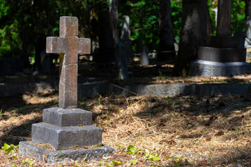 An image of a very old weathered stone cross in a long forgotten cemetery. 