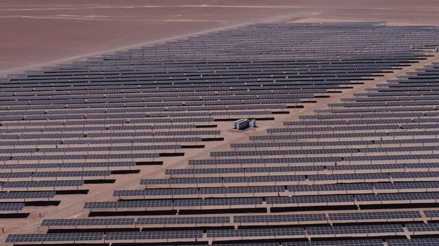 drone captura uma vista a&eacute;rea de um parque solar no deserto, exibindo c&eacute;lulas fotovoltaicas e m&oacute;dulos solares sob o c&eacute;u ensolarado