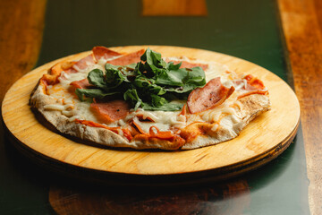 A delicious pizza is sitting on a wooden plate atop a wooden table