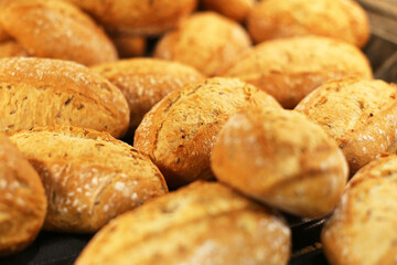 Fresh Kaiser rolls stacked on a store shelf. Group of classic bread rolls on display. Bakery section with a pile of golden brown buns. Perfect for sandwiches or breakfast. Crisp, freshly baked roll.