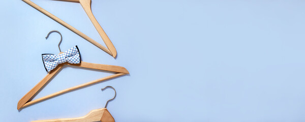 Hanger with checkered bow-tie surrounded by other clothes hangers. Men sale banner. Selective focus, copy space