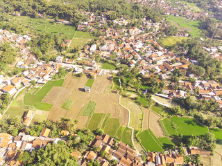 Photography of a patch of rice fields under a hill. A green rice fields sandwiched between hills and countryside in Bandung - Indonesia. Residential District. Panoramic Landscape photography concept.