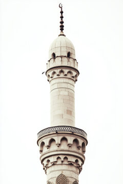 A beautifully detailed white mosque minaret stands tall against a clear sky, with intricate architectural designs and a crescent moon at the top.