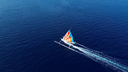 Indonesian fishing trimaran, traditional boat during fishing. Sailing trimaran in motion, drone view
