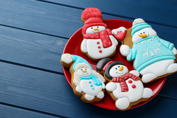 Delicious cookies in shape of snowmen on blue wooden table, closeup
