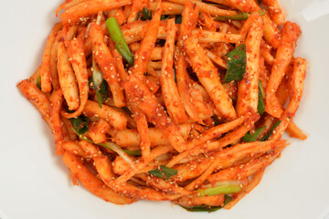 Korean food Seasoned Deodeok mixed with green onion and Kochujang(red pepper paste) in a white dish, South Korea.  Deodeok is Mountain herb whose roots have restorative properties