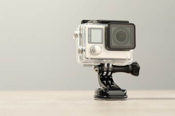 Modern action camera and mount on wooden table. Space for text